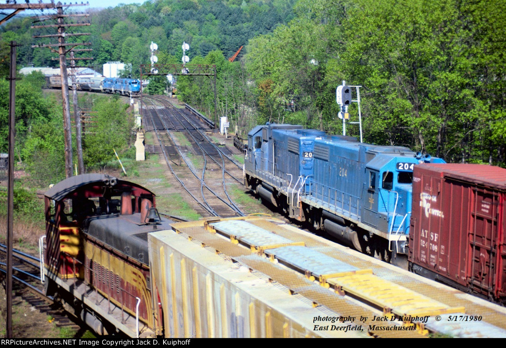 B&M, Boston and Maine GP40 300 leads a eastbound up to the signals as, B&M 201 westbound leaves the yard, and B&M 1223 switches cars. All trains were moving, at East Deerfield, Massachusetts. May 17, 1980. 